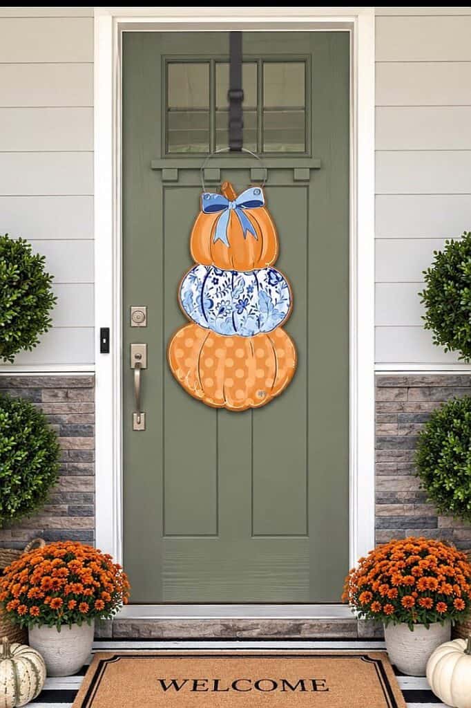 Decorative fall pumpkins with bow on front door for autumn decor.