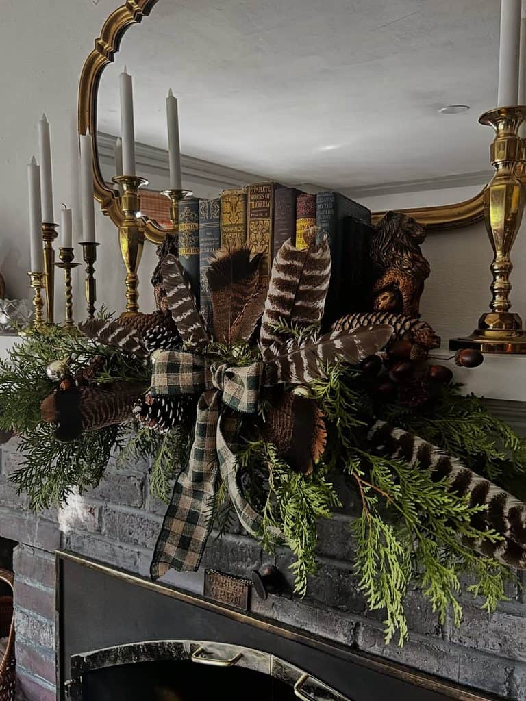 Autumn-themed mantel decor with books, feathers, and greenery.