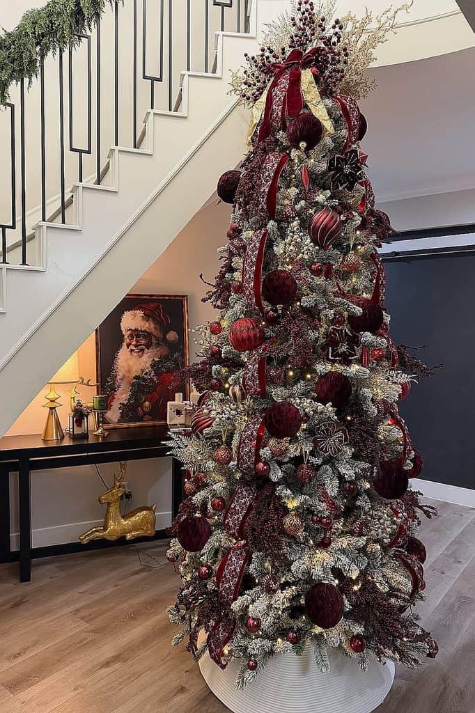 Elegant Christmas tree decorated with burgundy ornaments and ribbons in a modern home.