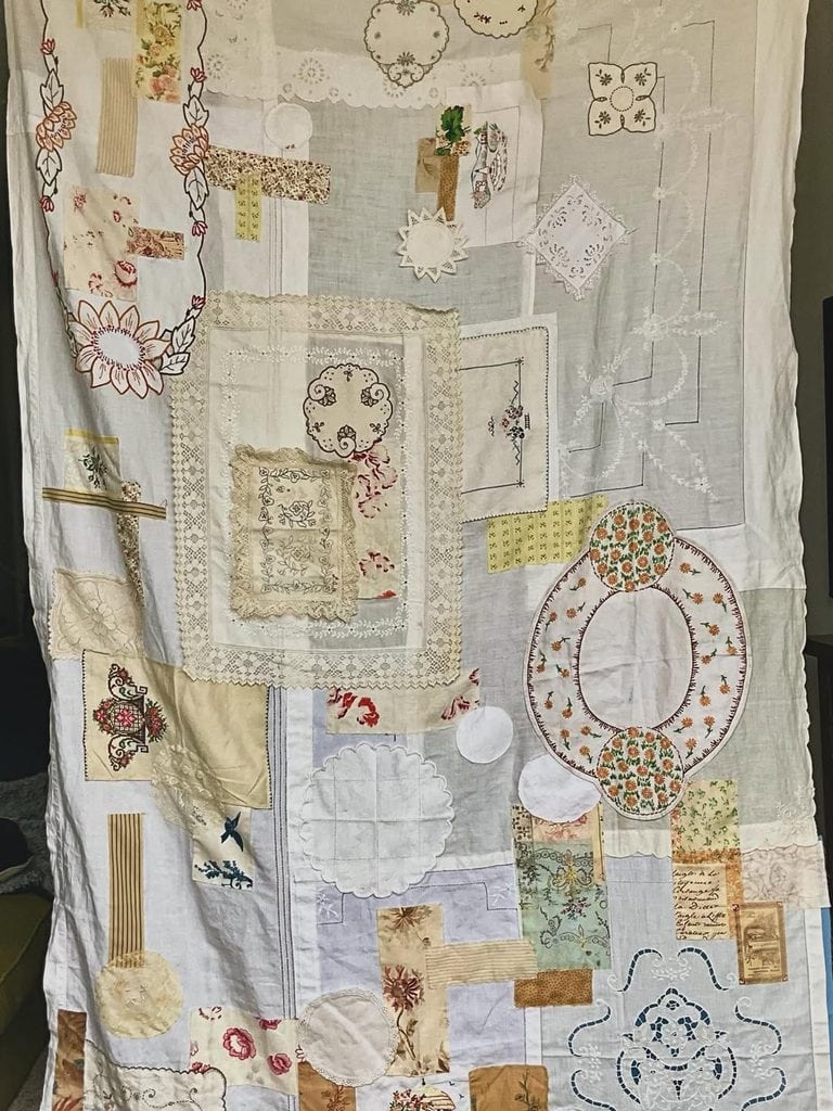 Assorted vintage doilies and embroidered linens arranged on a fabric background.
