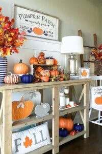 Autumn pumpkin arrangement with orange, white, and blue pumpkins on a wooden table.
