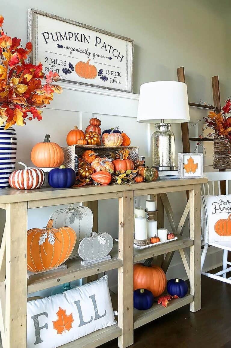 Autumn pumpkin arrangement with orange, white, and blue pumpkins on a wooden table.