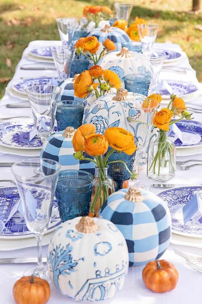 Elegant blue and orange fall table decor with pumpkins and flowers.