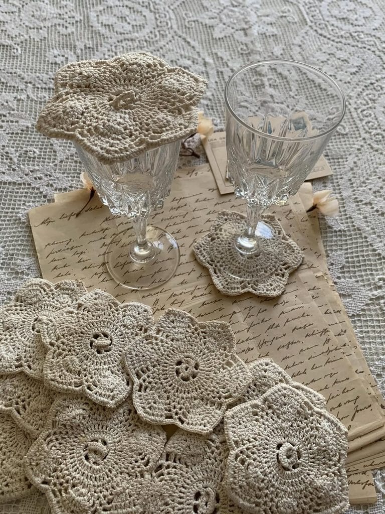 Decorative vintage doilies with glassware on lace tablecloth for repurposing ideas.