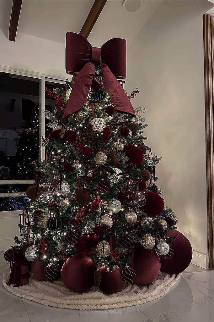 Beautiful Christmas tree with burgundy ornaments and a large bow topper.