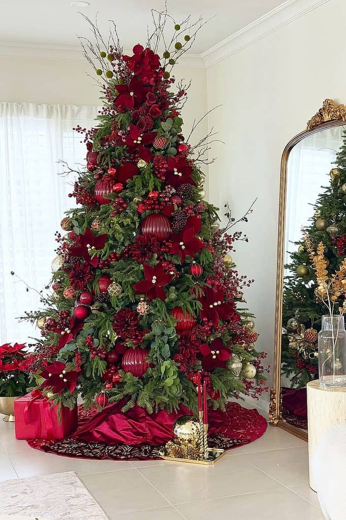 Beautiful burgundy Christmas tree with ornaments, poinsettias, and greenery in a festive setting.