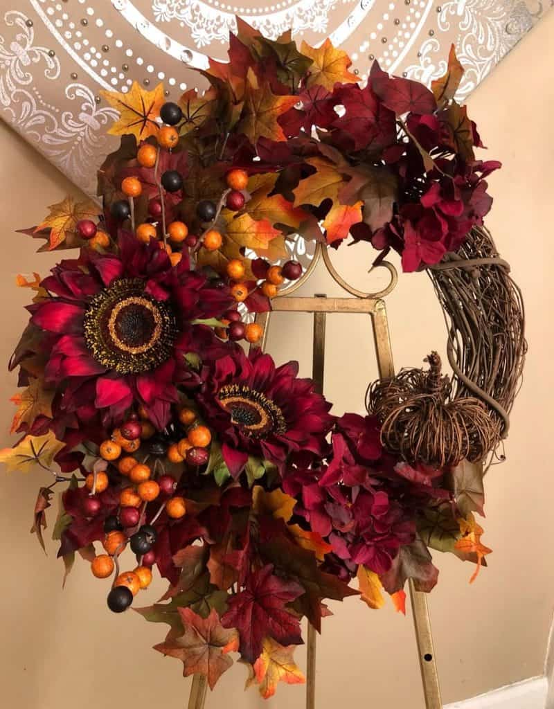 Decorative fall wreath with sunflowers, berries, and colorful autumn leaves.