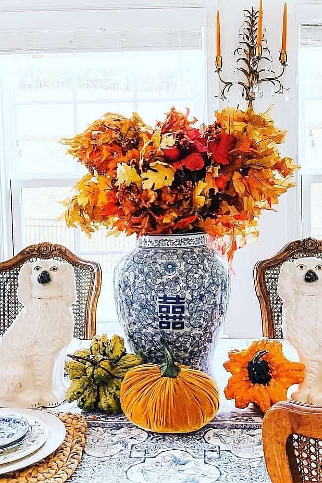 Fall floral arrangement with pumpkins and autumn leaves for seasonal decor.