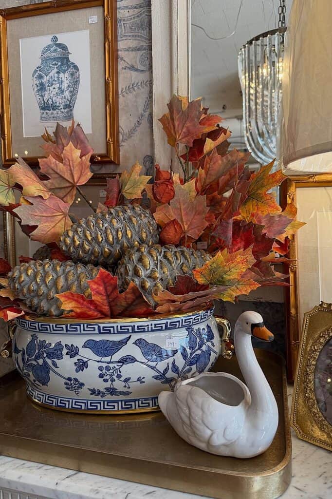 Fall decor with pinecones, autumn leaves, and elegant vases in a vintage setting.