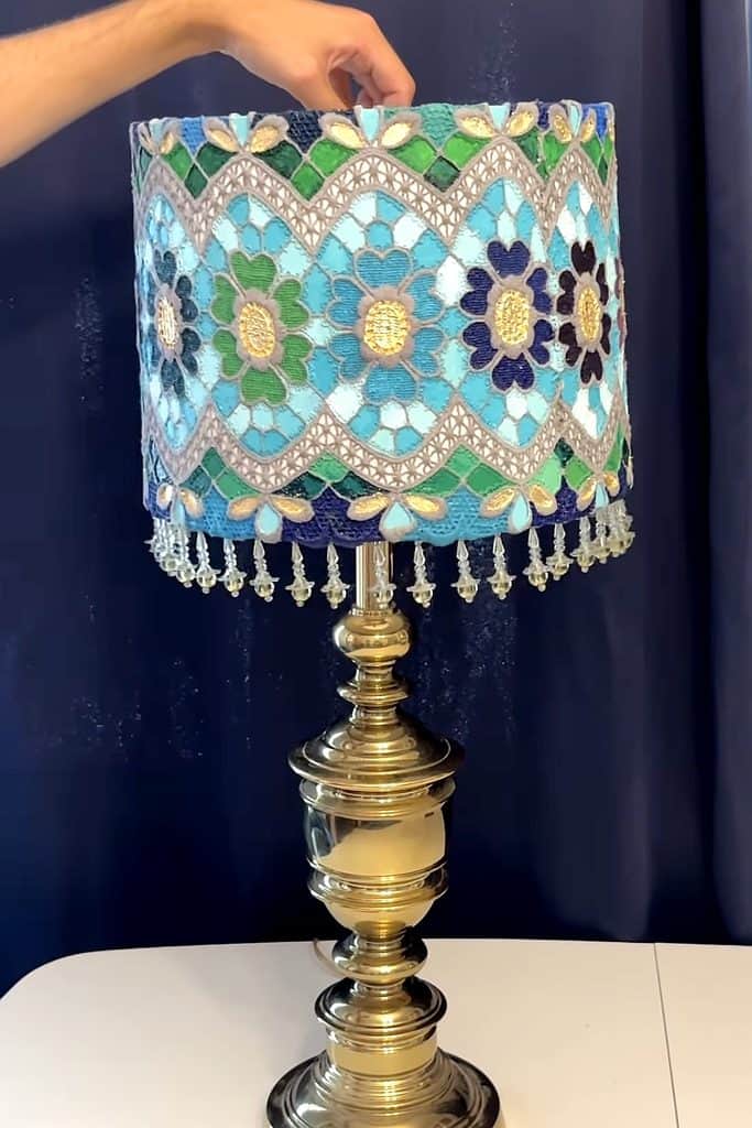 Decorative lamp with a vibrant, handcrafted doily lampshade featuring floral patterns.