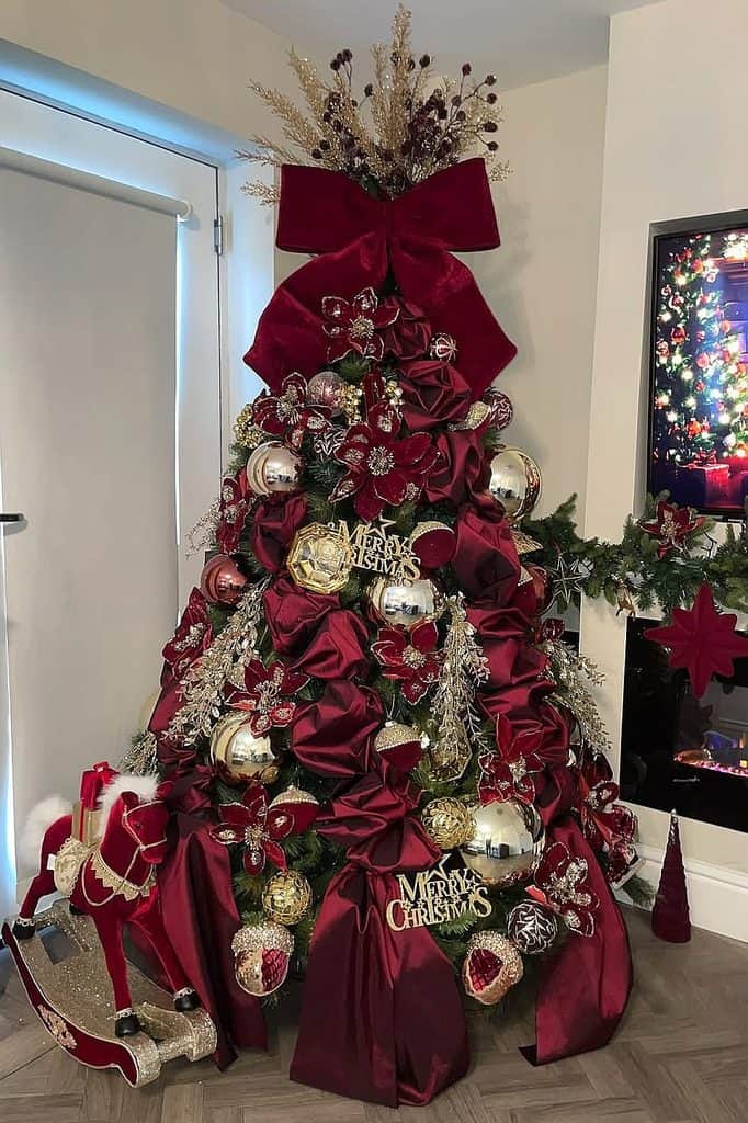 Burgundy Christmas tree with ornaments, ribbons, and festive decorations.