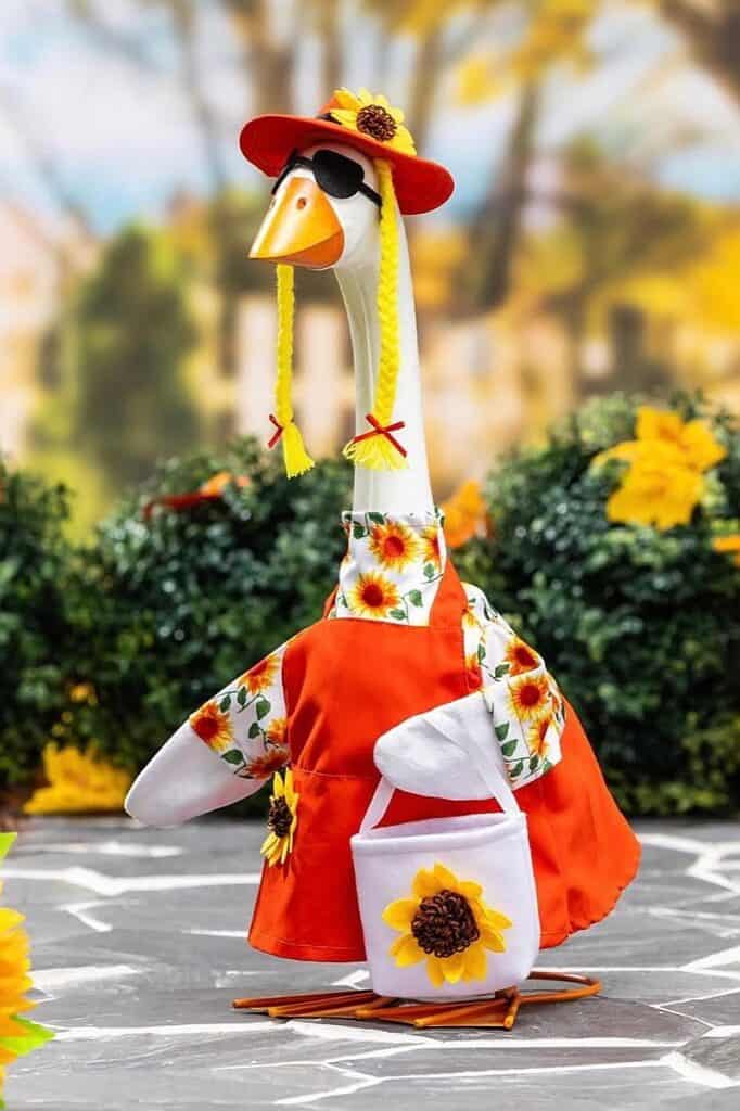 Decorative fall-themed goose figurine with sunflower dress and hat for porch decor.