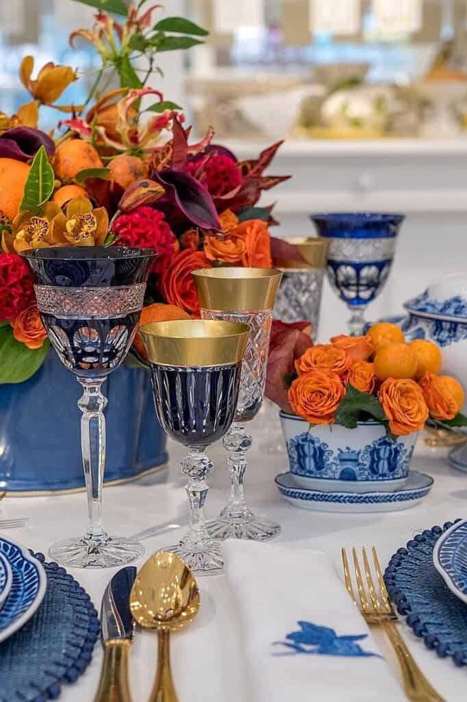Elegant blue and orange fall table decor with flowers and gold accents.