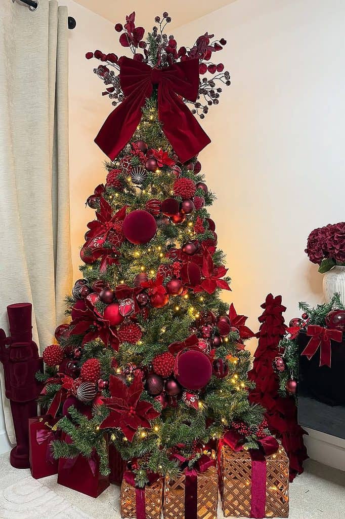 Elegant burgundy Christmas tree with ornaments, ribbons, and lights for holiday decor.