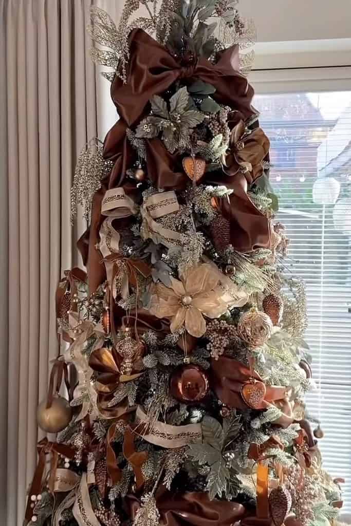 Cozy Christmas tree decorated with brown ribbons, ornaments, and gold accents.