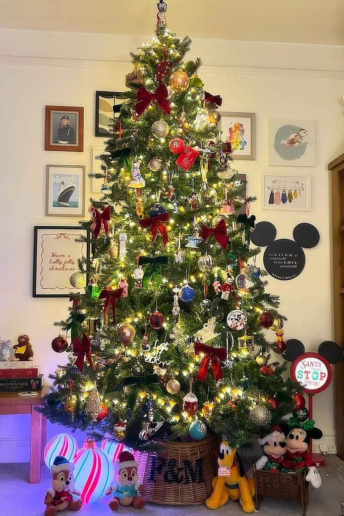 Decorated Christmas tree with Disney ornaments, lights, and holiday figures.