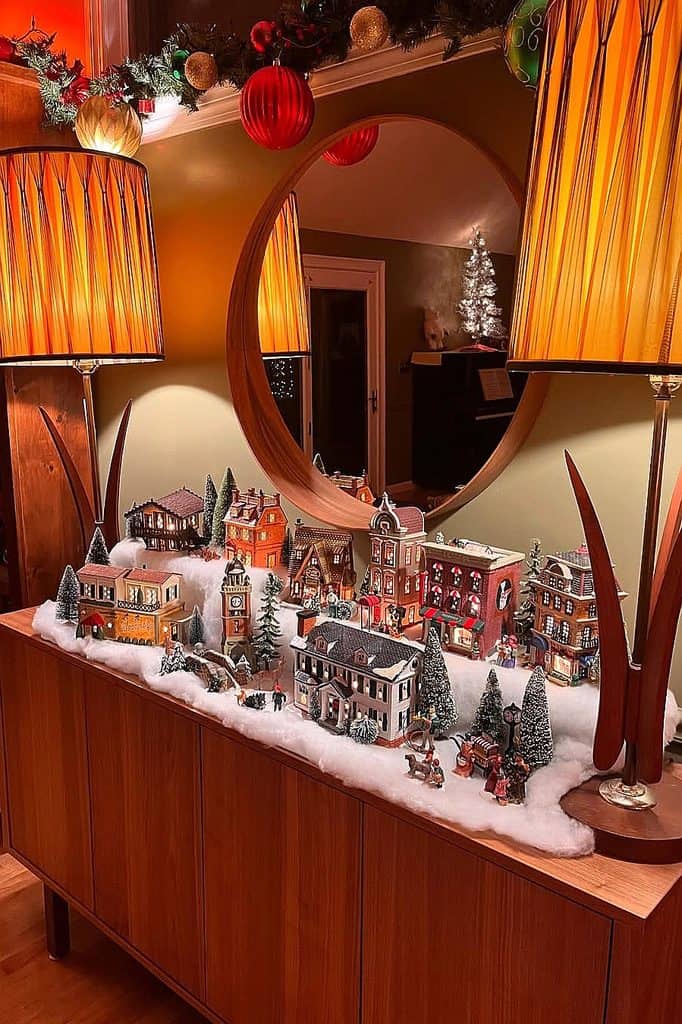 Festive Christmas village display with miniature buildings and snow decor.