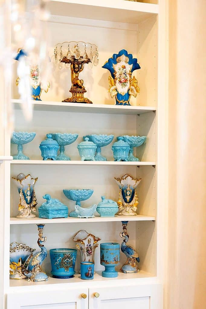 Collection of vintage milk glass and porcelain decorative items on a white shelf.