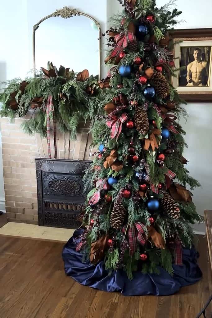 Decorated Christmas tree with ornaments, ribbons, and pinecones in a cozy home setting.