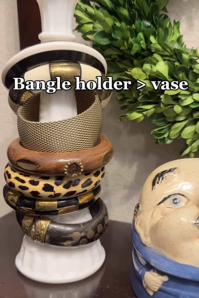Stylish bangle holder used as a vase with jewelry and greenery.