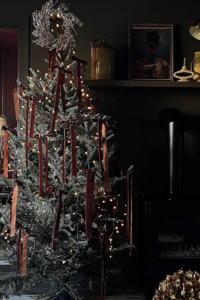 Decorated Christmas tree with red candles and silver ornaments in cozy home.