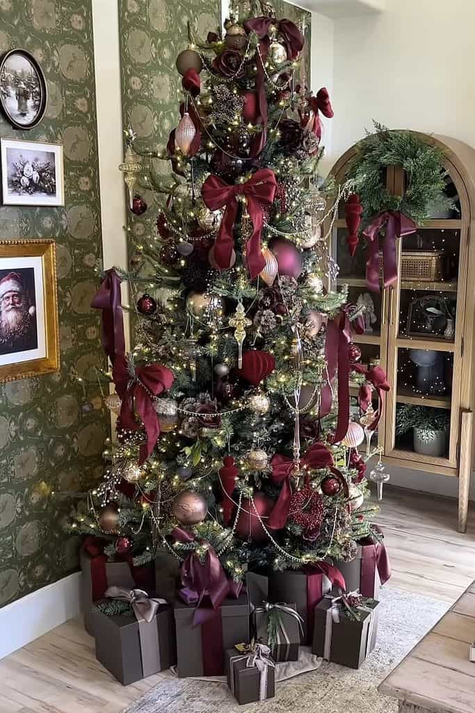 Festive Christmas tree decorated with burgundy ribbons, ornaments, and lights.