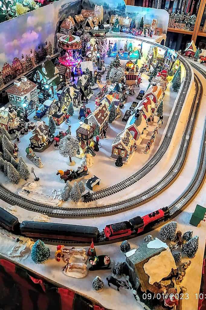 Detailed Christmas village with trains, houses, and festive decorations.