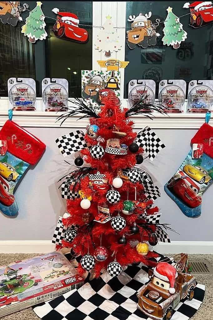 Red Christmas tree decorated with Cars-themed ornaments and checkered ribbons.