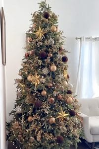 Beautiful brown Christmas tree decorated with gold, pink, and purple ornaments and stars.