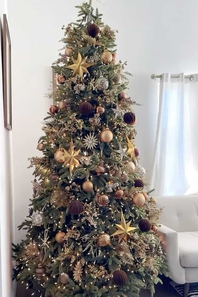 Beautiful brown Christmas tree decorated with gold, pink, and purple ornaments and stars.