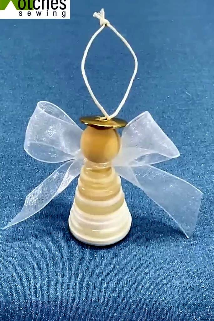 Handmade angel ornament with a button body, ribbon wings, and a hanging loop.