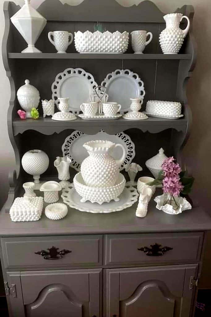 Elegant milk glass vases and dishes on a vintage hutch for charming home decor.