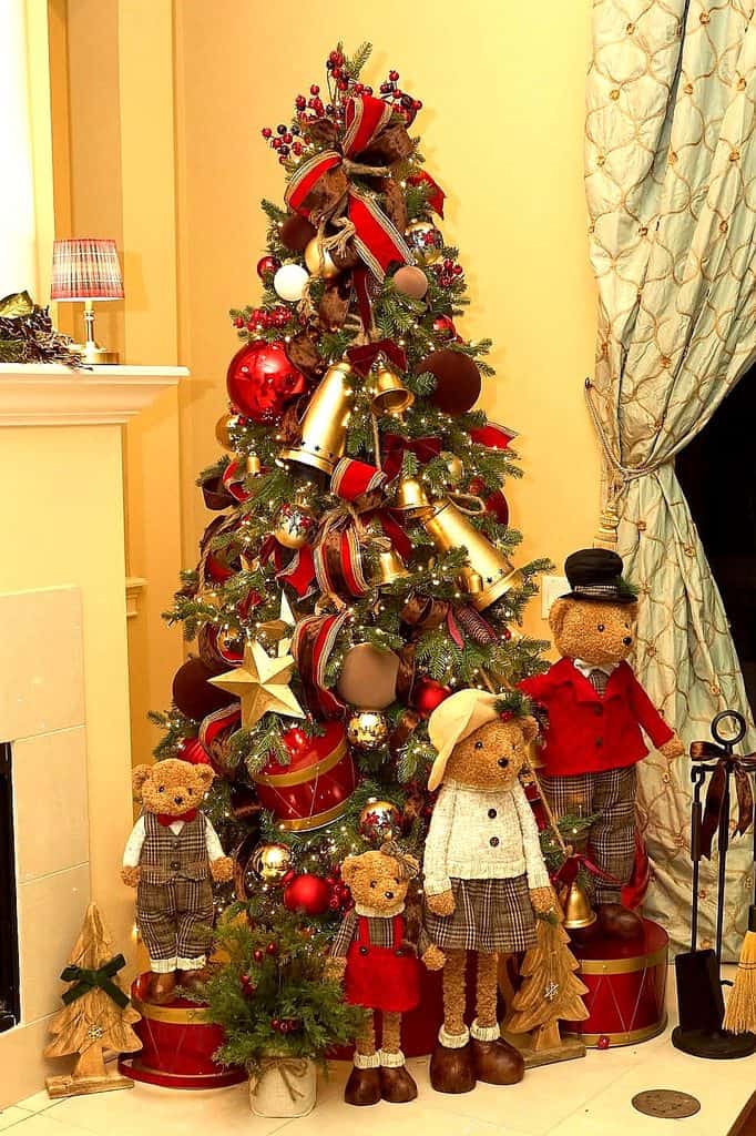 Decorated Christmas tree with ornaments, ribbons, and holiday dolls in a cozy room.
