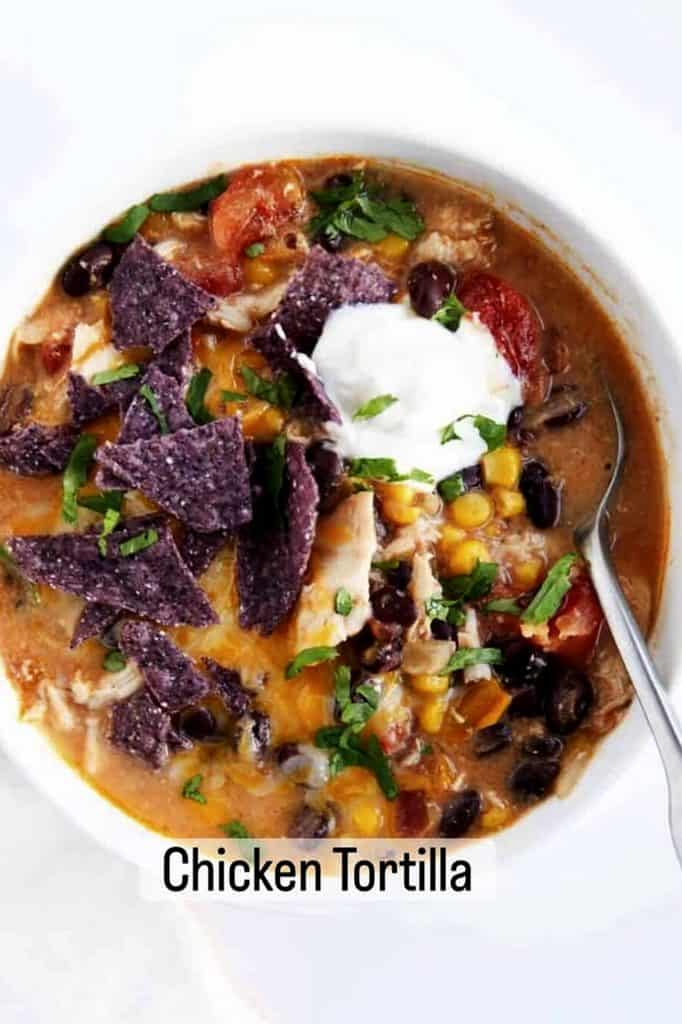 Hearty chicken tortilla soup with corn, beans, tomatoes, and cheese, garnished with cilantro.