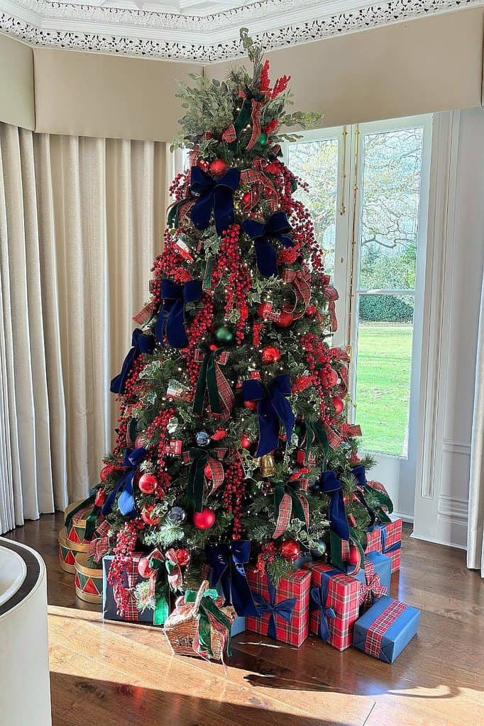 Decorated Christmas tree with red, blue ribbons and wrapped presents.