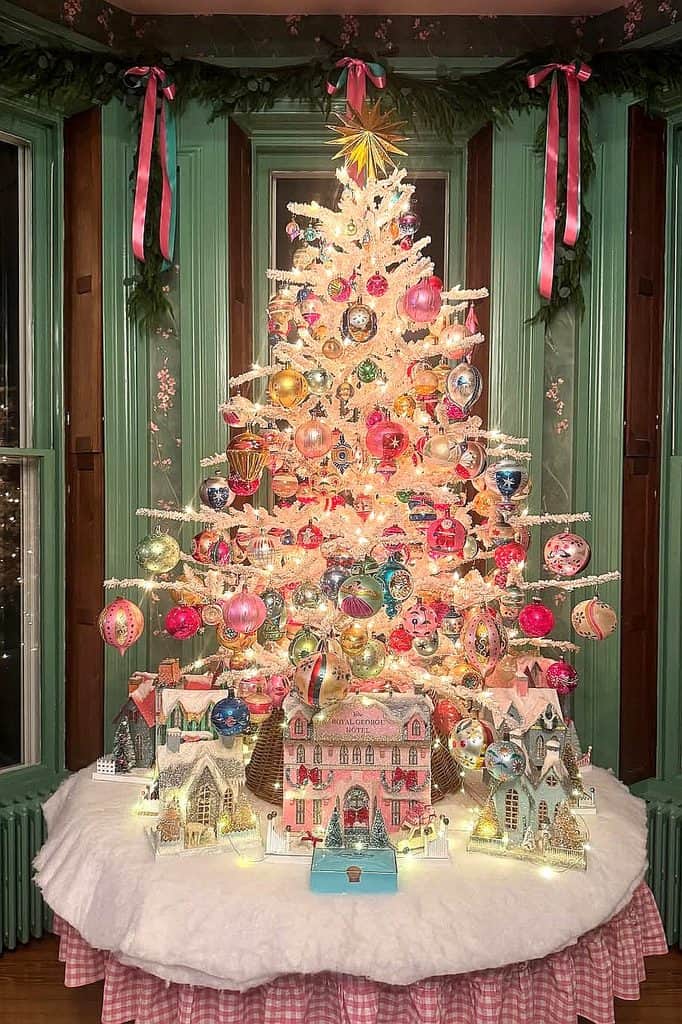 Festive Christmas village display with decorated tree and ornaments.