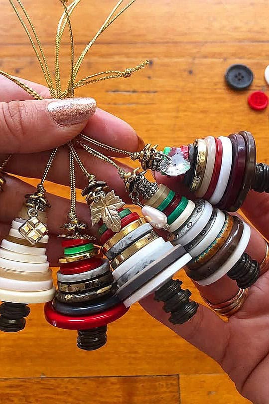 Colorful Christmas button craft ornaments with gold string for holiday decor.