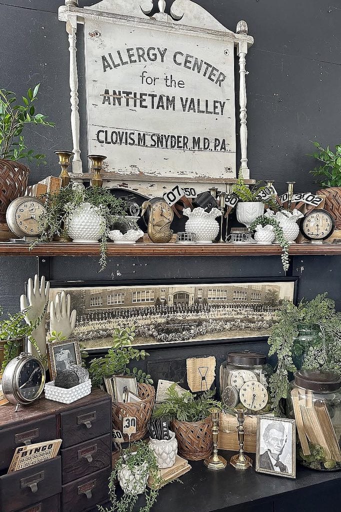 Eclectic vintage decor with clocks, plants, and antique medical sign.