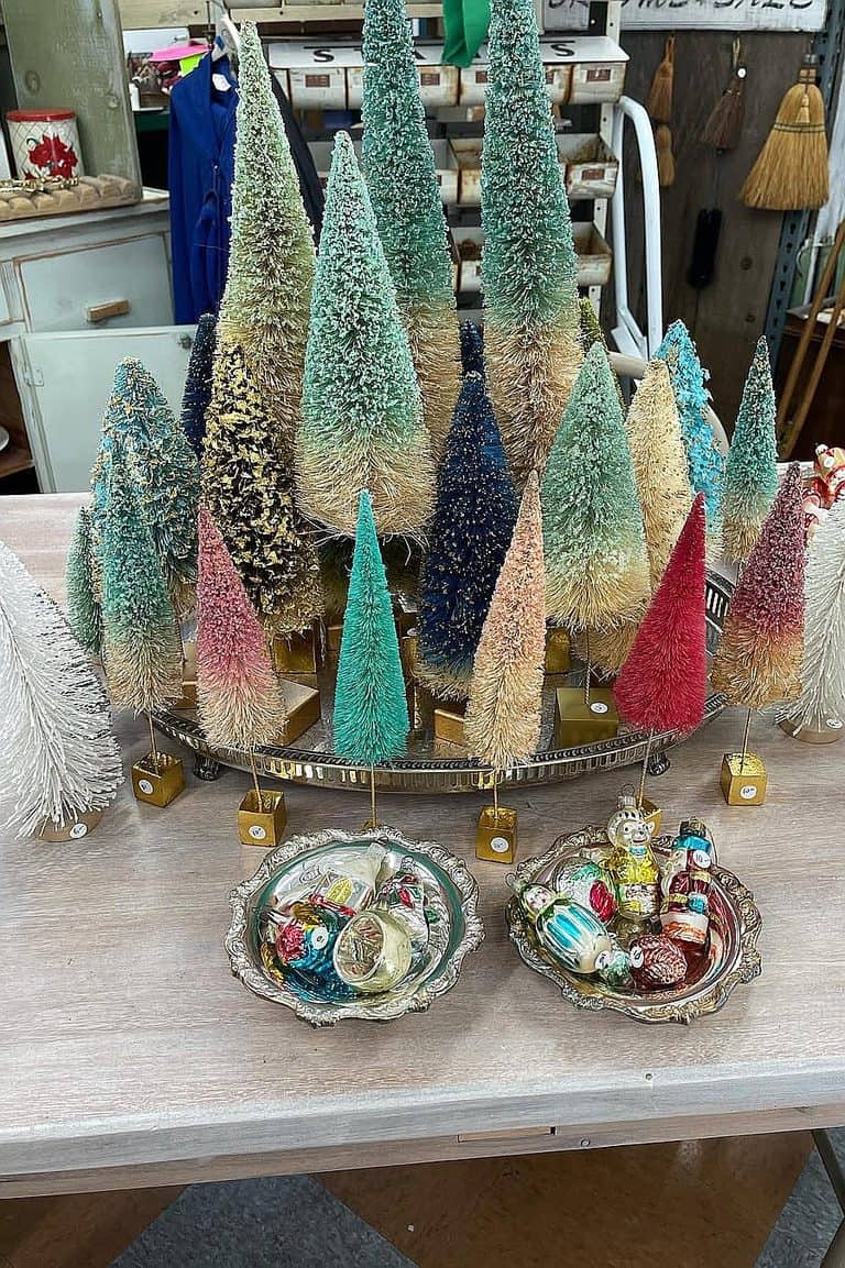 Assorted colorful Christmas trees with ornaments and decorations on a table.