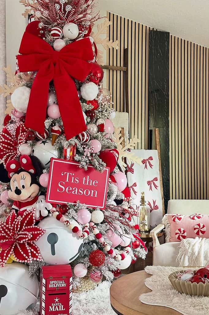 Festive Christmas tree with ornaments, ribbons, and Mickey Mouse decoration in holiday setting.